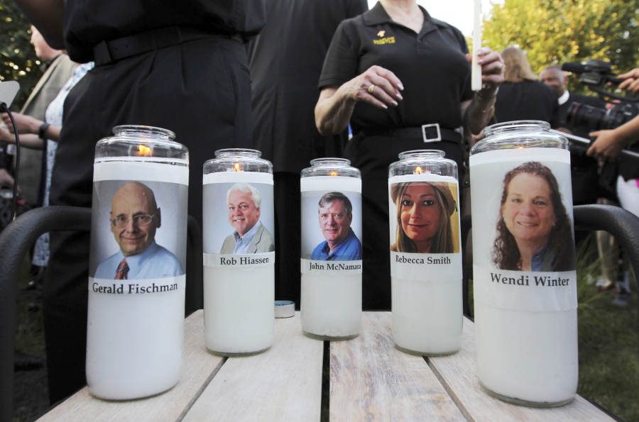FILE - In this June 29, 2018, file photo, pictures of five employees of the Capital Gazette newspaper adorn candles during a vigil across the street from where they were slain in the newsroom in Annapolis, Md. A jury was selected on Friday, June 25, 2021, for the second phase of a trial for a man who killed the five people at the newspaper to decide whether he is criminally responsible due to his mental health. Jarrod Ramos pleaded guilty in 2019 to all 23 counts against him in the attack at the Capital Gazette nearly three years ago, but he has pleaded that he is not criminally responsible due to mental illness.