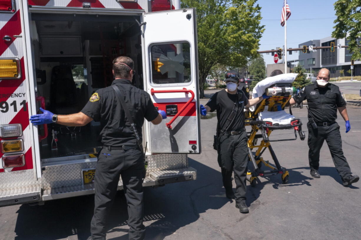 Salem Fire Department paramedics and employees of Falck Northwest ambulances respond to a heat exposure call during a heat wave, Saturday, June 26, 2021, in Salem, Ore.