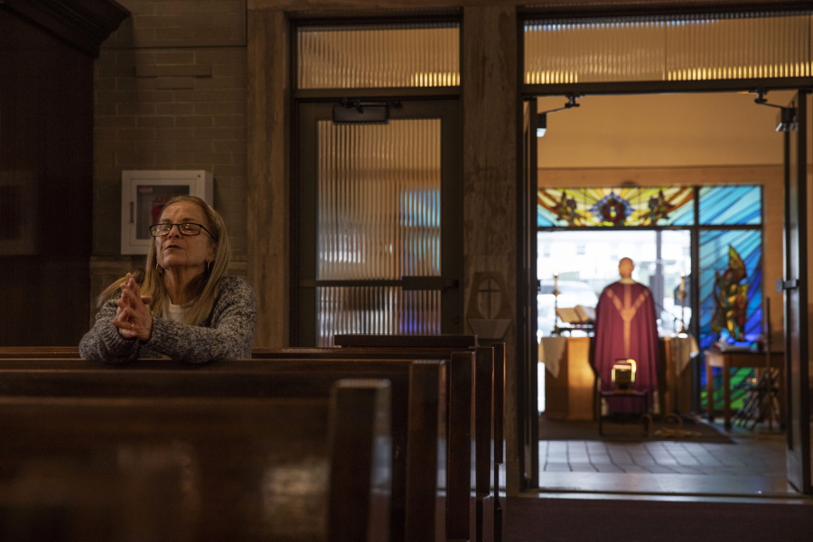 FILE - Fran DiBiasio sits alone in Our Lady of Grace Catholic Church as Rev. Peter Gower celebrates Mass from the front door as worshippers listen over the radio from their cars in the parking lot, Sunday, March 29, 2020, in Johnston, R.I. For the first time in nearly two decades, only half of U.S. households donated to a charity, according to a study released Tuesday, July 27, 2021.  Experts say many factors are contributing to the decline. The percentage of Americans who give to religious causes has decreased in tandem with attendance at worship services as the number of Americans not affiliated with any religion grows.