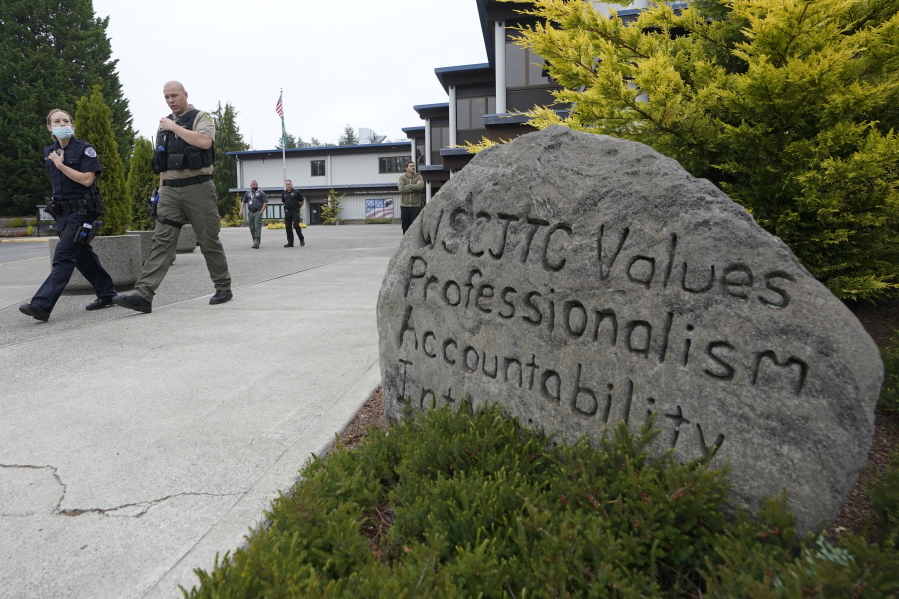 Cadets LeAnne Cone, left, of the Vancouver Police Dept., and Kevin Burton-Crow, right, of the Thurston Co. Sheriff's Dept., walk past a rock at the Washington state Criminal Justice Training Commission engraved with "WSCJTC Values Professionalism, Accountability Integrity," on the way to a training exercise Wednesday, July 14, 2021, in Burien, Wash. Washington state is embarking on a massive experiment in police reform and accountability following the racial justice protests that erupted after George Floyd's murder last year, with nearly a dozen new laws that took effect Sunday, July 25, but law enforcement officials remain uncertain about what they require in how officers might respond -- or not respond -- to certain situations, including active crime scenes and mental health crises. (AP Photo/Ted S.