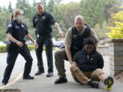 Kevin Burton-Crow, upper-right, of the Thurston Co. Sheriff's Dept., handcuffs Naseem Coaxum, right, an actor playing the role of a person causing a disturbance at a convenience store, during a training class at the Washington state Criminal Justice Training Commission, Wednesday, July 14, 2021, in Burien, Wash., instructor Ken Westphal, second from left, an officer with the Lacey Police Dept., and LeAnne Cone, left, of the Vancouver Police Dept., look on. Washington state is embarking on a massive experiment in police reform and accountability following the racial justice protests that erupted after George Floyd's murder last year, with nearly a dozen new laws that took effect Sunday, July 25 but law enforcement officials remain uncertain about what they require in how officers might respond -- or not respond -- to certain situations, including active crime scenes and mental health crises. (AP Photo/Ted S.