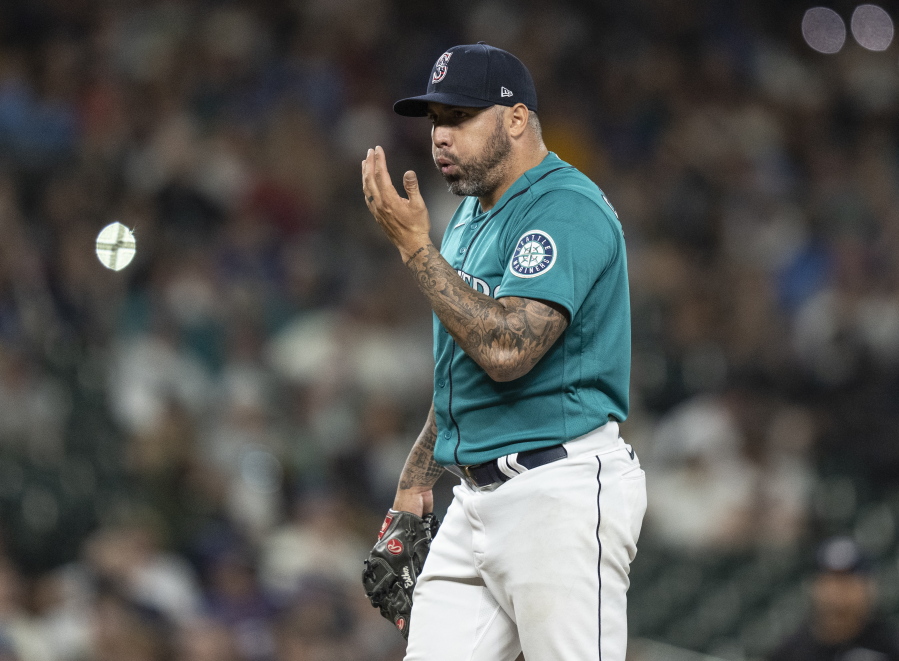 Seattle Mariners relief pitcher Hector Santiago blows on his hand between pitches during the eighth inning of the team's baseball game against the Texas Rangers, Friday, July 2, 2021, in Seattle.
