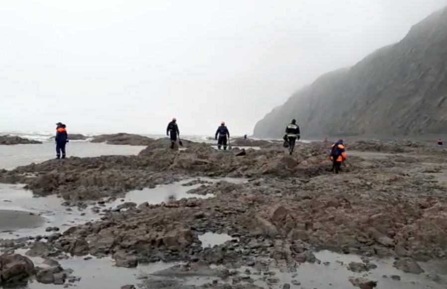 This photo taken from video released by the Russia Emergency Situations Ministry press service on Wednesday, July 7, 2021, shows Emergency Situations Ministry workers at the wreckage of a missing Antonov An-26 missing plane found near its destination airport outside the town of Palana, in Russia's Far East. Authorities in Russia say rescuers have found the bodies of nine victims a day after a plane crash in a remote area in the country's Far East.