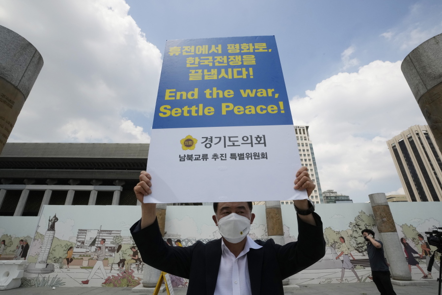 A man holds up a banner to demand the peace on the Korean peninsula near the U.S. Embassy in Seoul, South Korea, Tuesday, July 27, 2021. South Korea says the leaders of North and South Korea have agreed to restore suspended communication channels and improve ties.