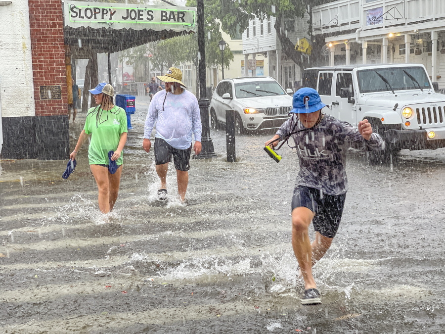Pedestrians dash across the intersection of Greene and Duval streets as heavy winds and rain associated with Tropical Storm Elsa passes Key West, Fla., on Tuesday, July 6, 2021. The weather was getting worse in southern Florida on Tuesday morning as Tropical Storm Elsa began lashing the Florida Keys, complicating the search for survivors in the condo collapse and prompting a hurricane watch for the peninsula's upper Gulf Coast.