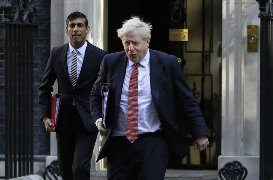FILE - In this Tuesday, Sept. 1, 2020 file photo, Britain's Prime Minister Boris Johnson and Chancellor Rishi Sunak, left, leave Downing Street to attend a cabinet meeting in London.  Johnson has been contacted by the country's test-and-trace system as a contact of a confirmed coronavirus case. The prime minister's office says that unlike most people, he won't have to self-isolate. But Johnson's office says the prime minister will instead take a daily coronavirus test as part of a pilot project. The same applies to Treasury chief Rishi Sunak, who also was contacted.