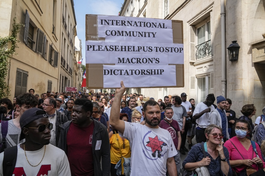 Anti-vaccine protester holds a placard during a rally in Paris, Saturday, July 17, 2021. Tens of thousands of people protested across France on Saturday against the government's latest measures to curb rising COVID-19 infections and drive up vaccinations in the country.