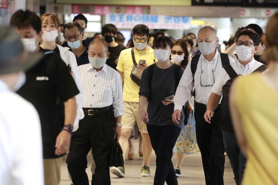 People wearing face masks to protect against the spread of the coronavirus walk at a train station in Tokyo Wednesday, July 28, 2021. Tokyo Gov. Yuriko Koike on Wednesday urged younger people to cooperate with measures to bring down the high number of infections and get vaccinated, saying their activities are key to slowing the surge during the Olympics. On Tuesday, the Japanese capital reported 2,848 new cases, exceeding its previous record in January.
