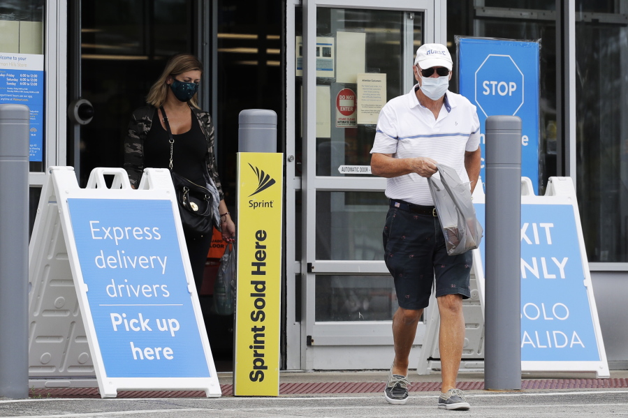 FILE - In this July 30, 2020 file photo, shoppers wear face masks as they leave a Walmart store in Vernon Hills, Ill.  Walmart is reversing its mask policy, Friday, July 30, 2021, and will require vaccinated workers in its distribution centers and stores in areas to wear masks in areas with high infection rates of the virus.  (AP Photo/Nam Y.