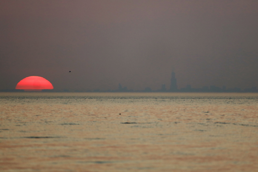 As the sun sets, the Chicago skyline appears through haze emitted from the American West, Tuesday, July 27, 2021, in Indiana Dunes State Park, in Indiana. Wildfires in the American West, including one burning in Oregon that's currently the largest in the U.S., are creating hazy skies as far away as New York.