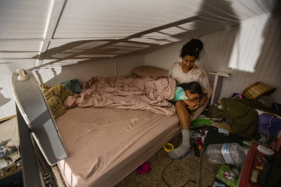 Camp fire victim and volunteer firefighter Inez Salinas holds her 5-year-old daughter River at bedtime inside their tiny home on July 22, 2021 in Concow, California.