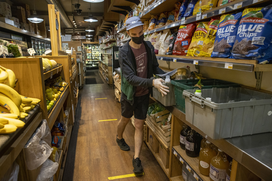 Grocery clerk Matt Sawyer organizes containers used to keep home-delivery and curbside pickup items together at Weavers Way Co-op in Philadelphia's Mount Airy section. (Alejandro A.