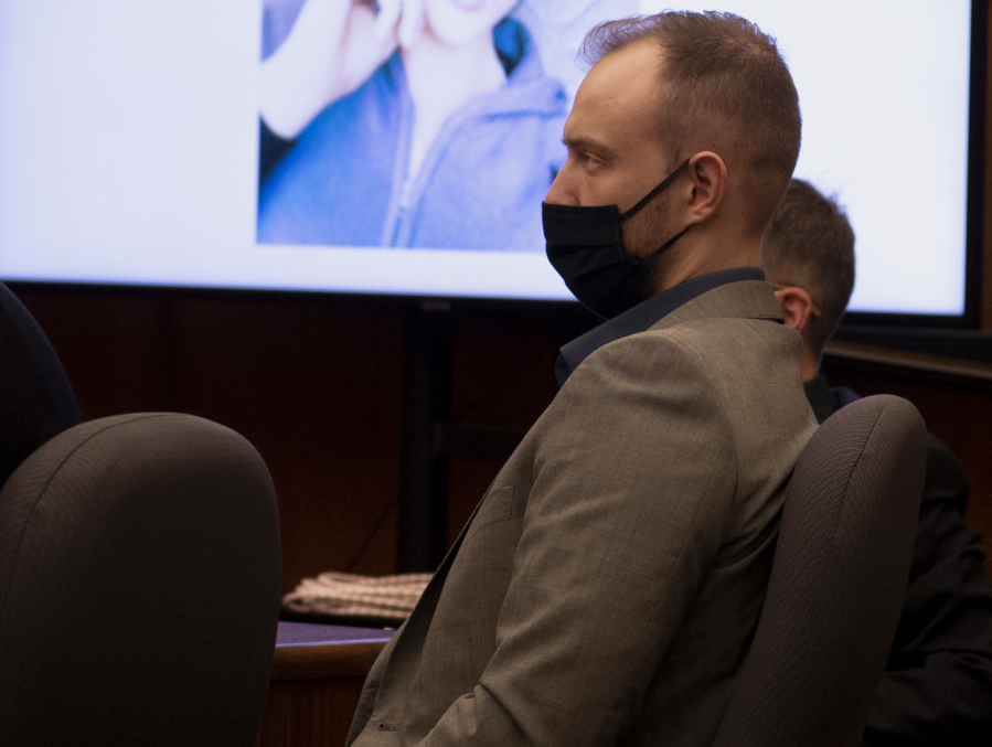 Defendant David Bogdanov listens to the prosecution's opening statement, with a photo of 17-year-old Nikki Kuhnhausen on a projection screen behind him, at his murder trial in Clark County Superior Court.