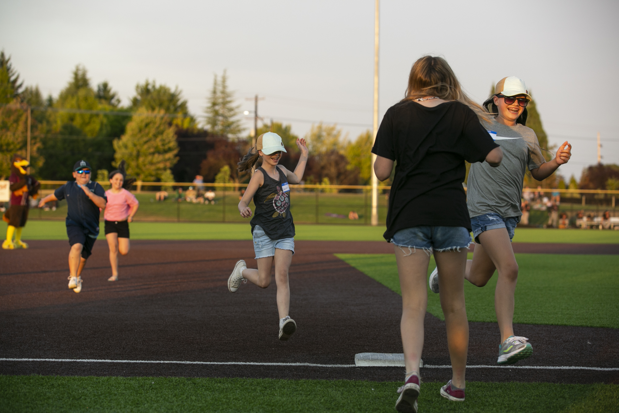 Young baseball fans run the bases in a game against Ridgefields' team Mascot, Rally the Raptor, between innings at Ridgefield Outdoor Recreation Complex on Wednesday, August 4, 2021.