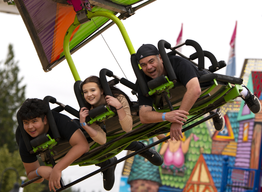 Jordan Higgins, from left, Kyra Tiaga and Ted Tiaga smile as they ride "Cliff Hanger" on Saturday at the Clark County Fairgrounds. While the fair was canceled this year, the Clark County Event Center is hosting several events in the Family Fun Series, including a carnival with rides and games. At top, inflatable aliens await the winners of the hammer game.