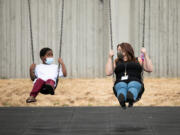 Kindergarten teacher Chelsea Hendryx shows incoming kindergartner Hakeem Hardnett, how to use the swings during recess at Hazel Dell Elementary School as part of Vancouver Public Schools' Jump Start program. Roughly 900 students across the distric attended Jump Start, a two-week program for students to familiarize themselves with rules and routines of school.