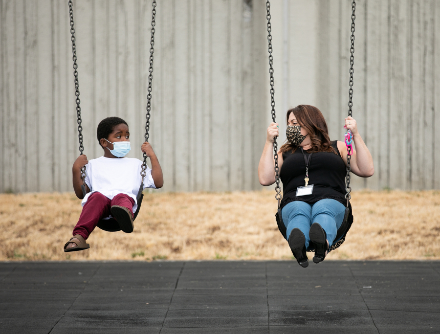 Kindergarten teacher Chelsea Hendryx shows incoming kindergartner Hakeem Hardnett, how to use the swings during recess at Hazel Dell Elementary School as part of Vancouver Public Schools' Jump Start program. Roughly 900 students across the distric attended Jump Start, a two-week program for students to familiarize themselves with rules and routines of school.