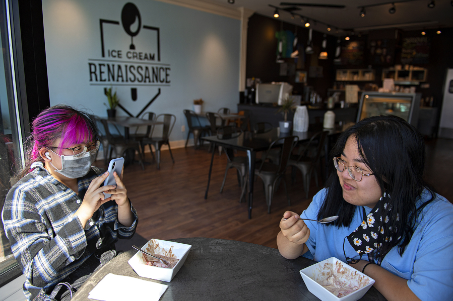 Jennifer Le of Vancouver, left, enjoys a treat at Ice Cream Renaissance in Uptown Village with her sister, Julie, on Monday afternoon. Washington's renewed indoor mask mandate took effect Monday.