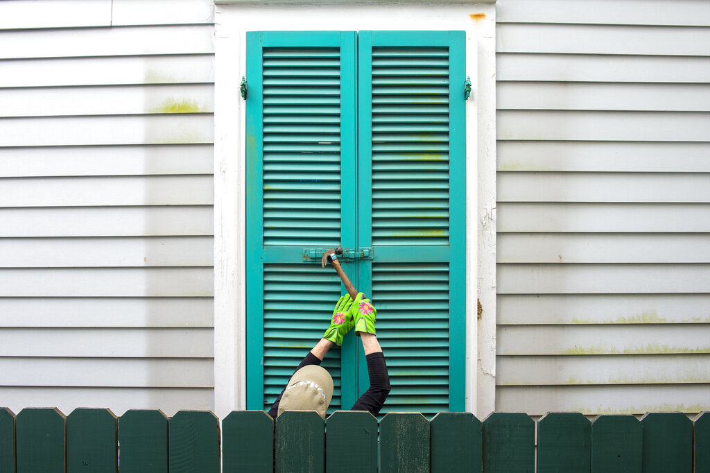 Storm shutters are hammered closed on a 100-year-old house, Friday, August 27, 2021, in New Orleans, as residents prepare for Hurricane Ida.