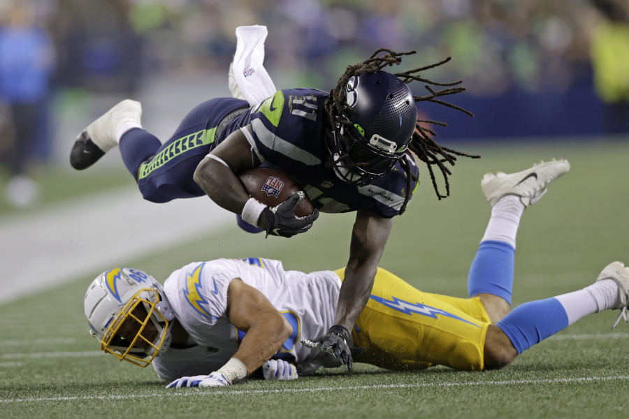 Seattle Seahawks running back Alex Collins dives over Los Angeles Chargers safety Ben DeLuca as he carries the ball during the second half of an NFL football preseason game, Saturday, Aug. 28, 2021, in Seattle.