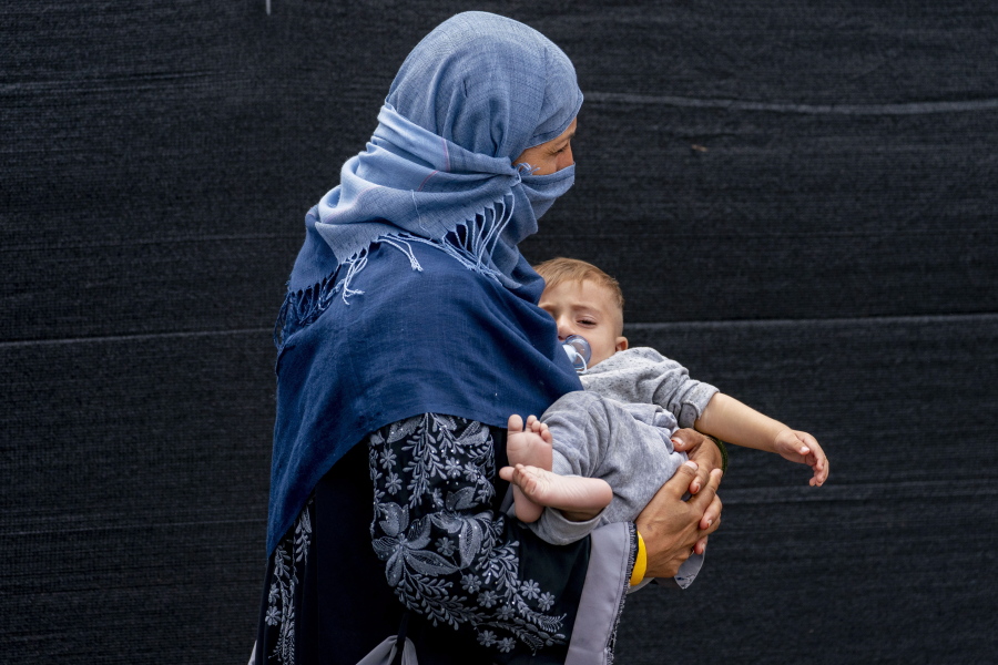 A woman evacuated from Afghanistan steps off a bus with a baby as they arrive at a processing center in Chantilly, Monday, Aug. 23, 2021, after arriving on a flight at Dulles International Airport.
