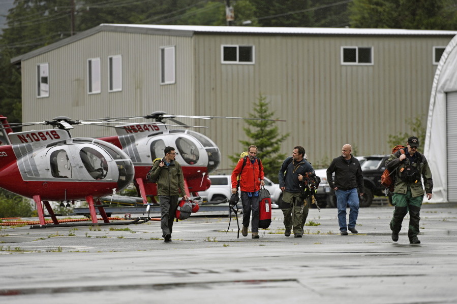Ketchikan Volunteer Rescue Squad personnel land and disembark from a Hughes 369D helicopter on Thursday, Aug. 5, 2021, at Temsco Helicopters Inc in Ketchikan, Alaska. The KVRS, U.S. Coast Guard, Alaska State Troopers and U.S. Forest Service responded to a radio beacon alert from a downed Southeast Aviation de Havilland Beaver float plane that was carrying five passengers from the Holland America Line cruise ship Nieuw Amsterdam, according to Coast Guard, Holland America and KVRS information. The sightseeing plane crashed Thursday in southeast Alaska, killing all six people on board, the U.S. Coast Guard said.