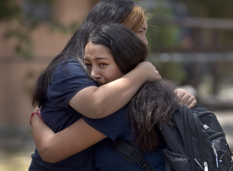 Students embrace after being released from school after a fatal shooting at Washington Middle School in Albuquerque, N.M., Friday, Aug. 13, 2021. New Mexico authorities say one student was killed and another was taken into custody following a shooting at a middle school near downtown Albuquerque during the lunch hour Friday.