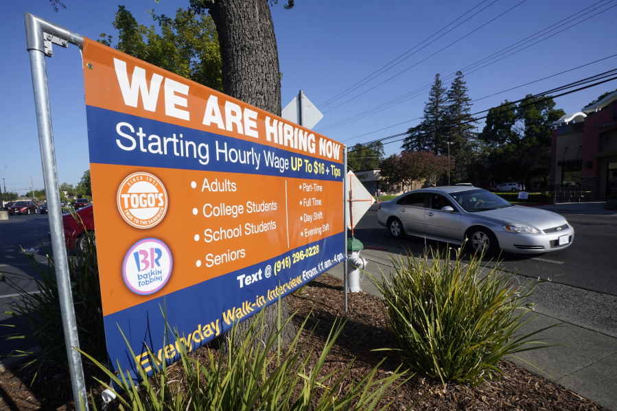A car passes a hiring banner in Sacramento, Calif., Friday, July 16, 2021. Hiring in California slowed down in June 2021 as employers in the nation's most populous state tried to coax reluctant workers back into their pre pandemic jobs before the nation's expanded unemployment benefits expire in September.