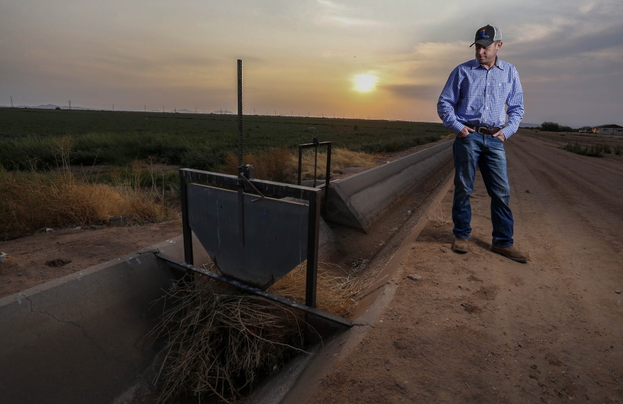 Will Thelander, a partner in his family's farming business, looks into a dry irrigation canal on his property, Thursday, July 22, 2021, in Casa Grande, Ariz. The Colorado River has been a go-to source of water for cities, tribes and farmers in the U.S. West for decades. But climate change, drought and increased demand are taking a toll. The U.S. Bureau of Reclamation is expected to declare the first-ever mandatory cuts from the river for 2022.