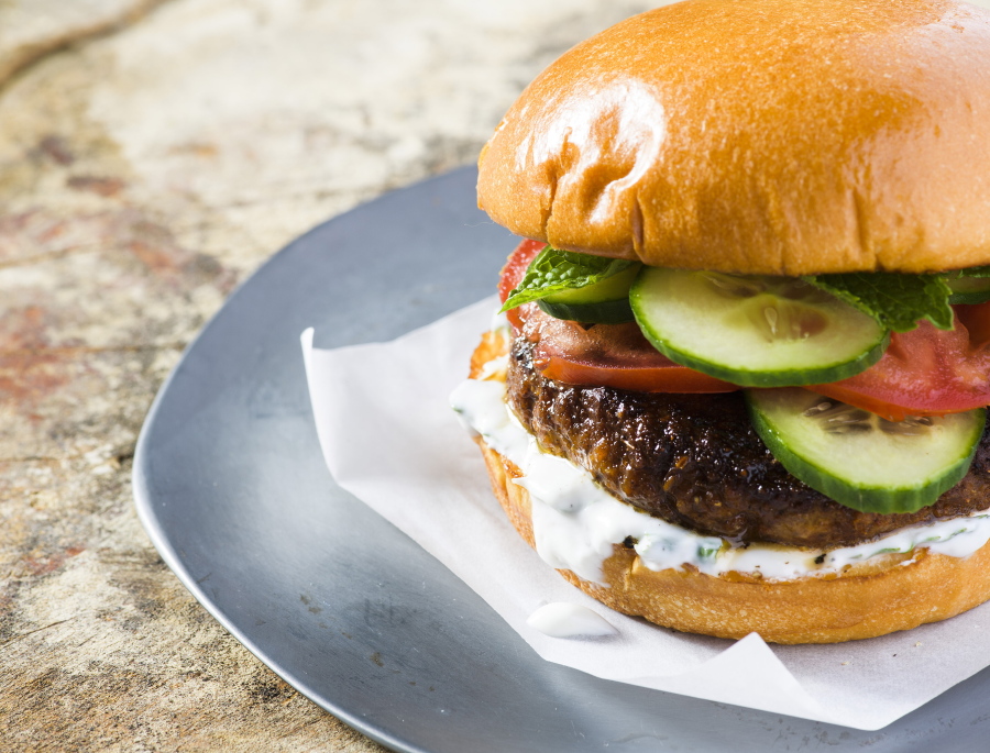This image released by Milk Street shows a recipe for Indian-spiced pork burgers. The garam masala, cayenne and cumin first are mixed into a paste made from tangy yogurt, egg yolk and breadcrumbs, which helps the burgers stay moist. Mixing the spiced paste into the meat ensures the flavor is distributed evenly throughout each burger.