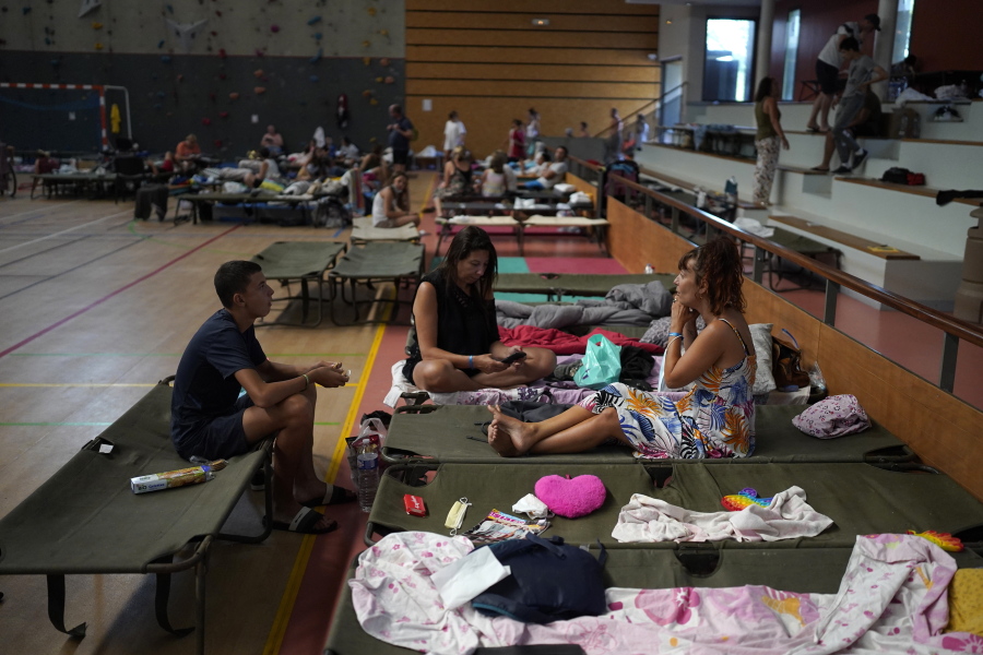 Evacuated campers rest in a gymnasium in Bormes-les-Mimosas, southern France, Wednesday, Aug. 18, 2021. Firefighters have been able to "stabilize" the blaze that raced Tuesday through forests near the French Riviera, forcing thousands of people to flee homes, campgrounds and hotels in a picturesque area beloved by residents and tourists alike..