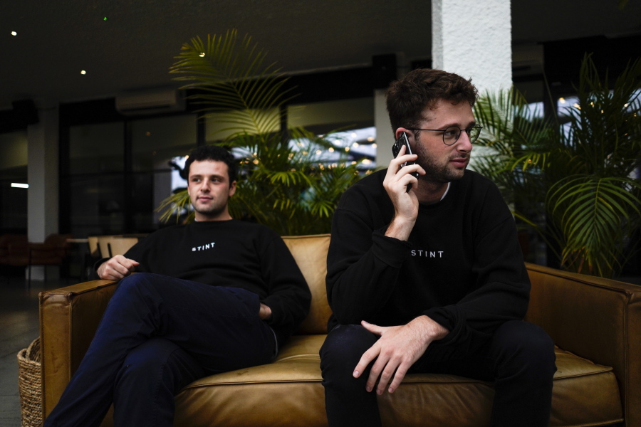 Co-founders of the app Stint, brothers Sam, left, and Sol Schlagman, sit on a couch, at their headquarters in Camden, London, Monday, Aug. 23, 2021. With Britain facing a pandemic and Brexit-induced labor shortage, some apps that recruit gig workers are playing a role in alleviating this shortage, such as Stint.