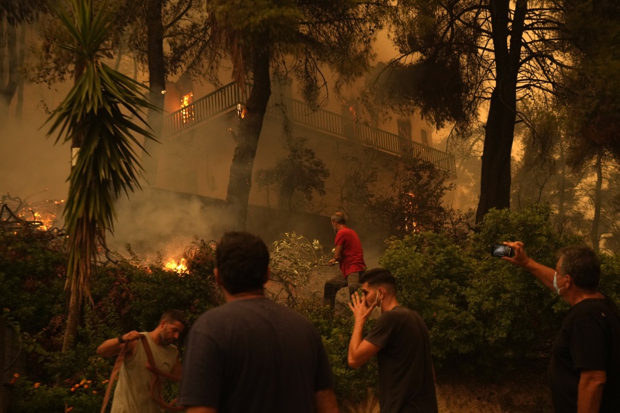 Flames burn a house at Pefki village on Evia island, about 189 kilometers (118 miles) north of Athens, Greece, Sunday, Aug. 8, 2021. Pillars of billowing smoke and ash are blocking out the sun above Greece's second-largest island as a days-old wildfire devours pristine forests and triggers more evacuation alerts.