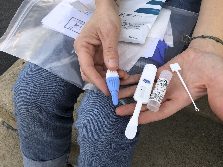 FILE - In this March 9, 2021 file photo,  Solutions Oriented Addiction Response organizer Brooke Parker displays an HIV testing kit in Charleston, W.Va.  Under the recommendations of an investigation led by the Centers for Disease Control and Prevention and released Tuesday, Aug.