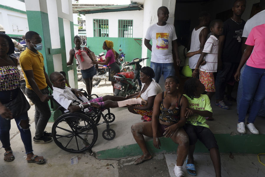 People injured in a car accident, sitting right, wait with others injured during the earthquake for x-rays at the General Hospital in Les Cayes, Haiti, Wednesday, Aug. 18, 2021.