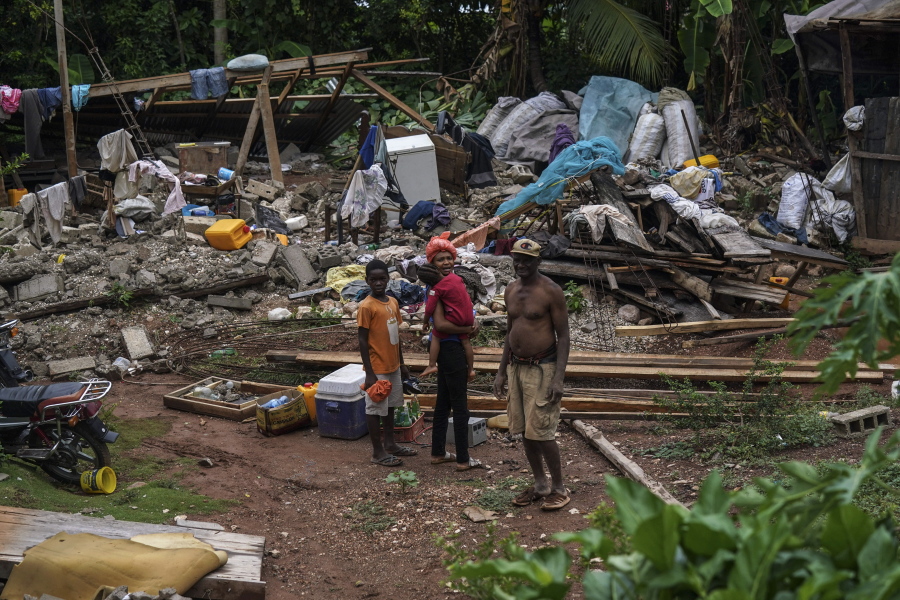 People recover belongings from the rubble of their home, destroyed by the earthquake in Fleurant, Haiti, Tuesday, Aug. 17, 2021, three days after the 7.2 -magnitude quake hit the Caribbean nation.