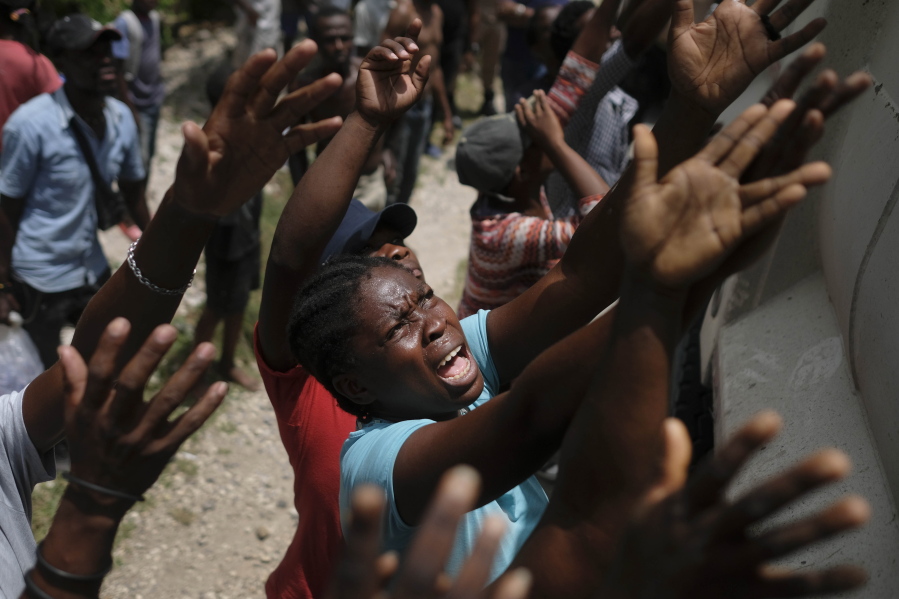 Earthquake victims reach for water being handed out during a food distribution in the Picot neighborhood in Les Cayes, Haiti, Sunday, Aug. 22, 2021, eight days after a 7.2 magnitude earthquake hit the area.