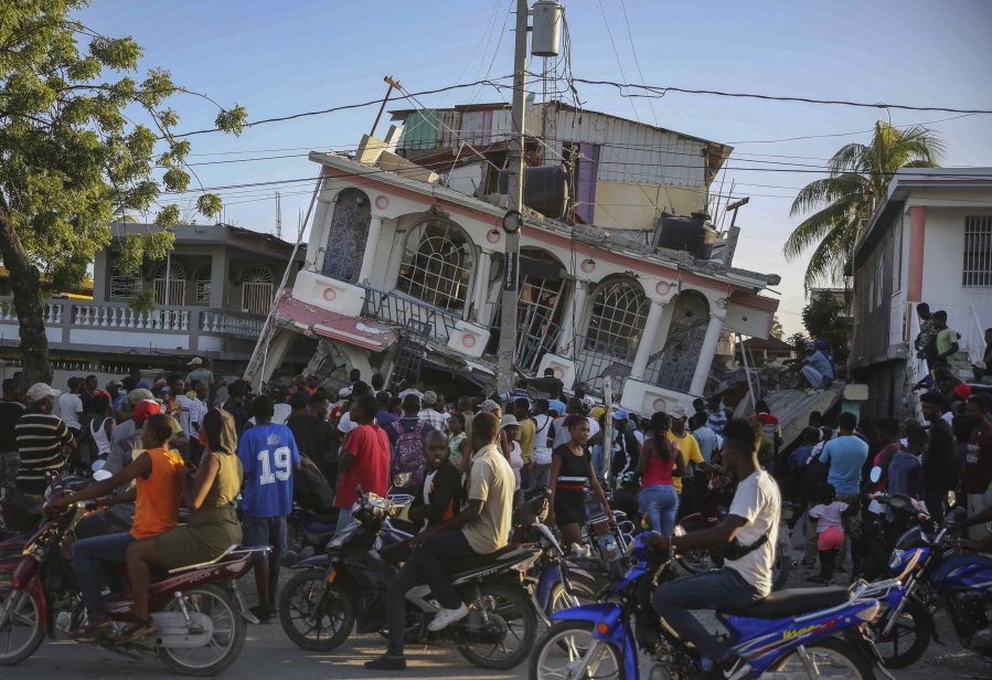 People gather outside the Petit Pas Hotel, destroyed by the earthquake in Les Cayes, Haiti, Saturday, Aug. 14, 2021. A 7.2 magnitude earthquake struck Haiti on Saturday, with the epicenter about 125 kilometers (78 miles) west of the capital of Port-au-Prince, the US Geological Survey said.