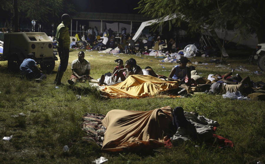 People displaced from their earthquake destroyed homes spend the night outdoors in a grassy area that is part of a hospital in Les Cayes, Haiti, late Saturday, Aug. 14, 2021. A powerful magnitude 7.2 earthquake struck southwestern Haiti on Saturday.