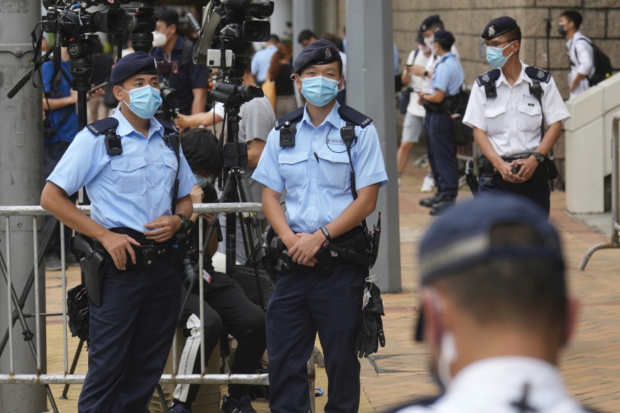 Police officers stand guard outside a court Friday, July 30, 2021, in Hong Kong, as a pro-democracy demonstrator Tong Ying-kit exits the court after his sentencing for the violation of a security law during a 2020 protest. Tong has been sentenced to nine years in prison in the closely watched first case under Hong Kong's national security law as Beijing tightens control over the territory.