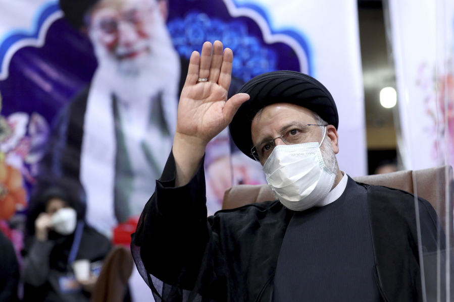 FILE - In this May 15, 2021 file photo, Ebrahim Raisi, then head of Iran's judiciary, waves to journalists while registering his candidacy for the upcoming presidential elections, in Tehran, Iran. Once President-elect Raisi, a prot?g? of Iran's Supreme Leader Ayatollah Ali Khamenei, shown in background, is sworn in as president this week, hard-liners will control all parts of the Islamic Republic's civilian government. Iran's inauguration of Raisi on Thursday represents the last stop in a slow slide from the hopes that the 2015 nuclear deal would open the Islamic Republic to the West.