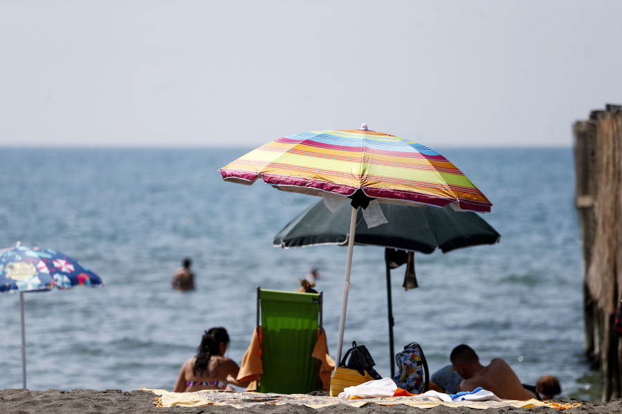 People enjoy a day at the beach, in Ostia, in the outskirts of Rome, Saturday, Aug. 14, 2021. A heat wave settled over southern Europe threatened temperatures topping 45 degrees  Celsius (113 degrees Fahrenheit) in many parts of the Iberian Peninsula on Saturday while Italian authorities expanded to 16 the number of cities on red alert for conditions that can pose a health risk to the elderly and vulnerable.