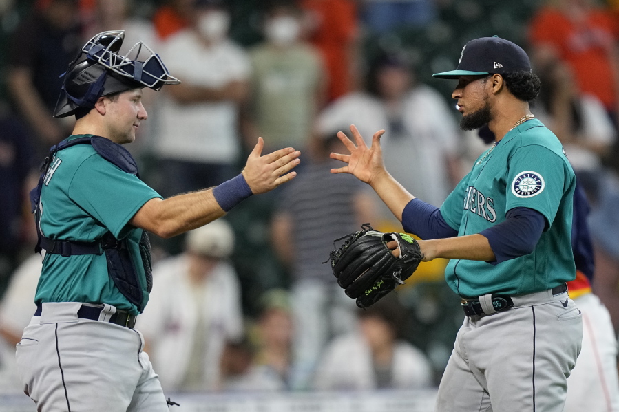 Seattle Mariners relief pitcher Yohan Ramirez, right, celebrates with catcher Cal Raleigh after a baseball game against the Houston Astros Sunday, Aug. 22, 2021, in Houston. The Mariners won 6-3 in 11 innings. (AP Photo/David J.