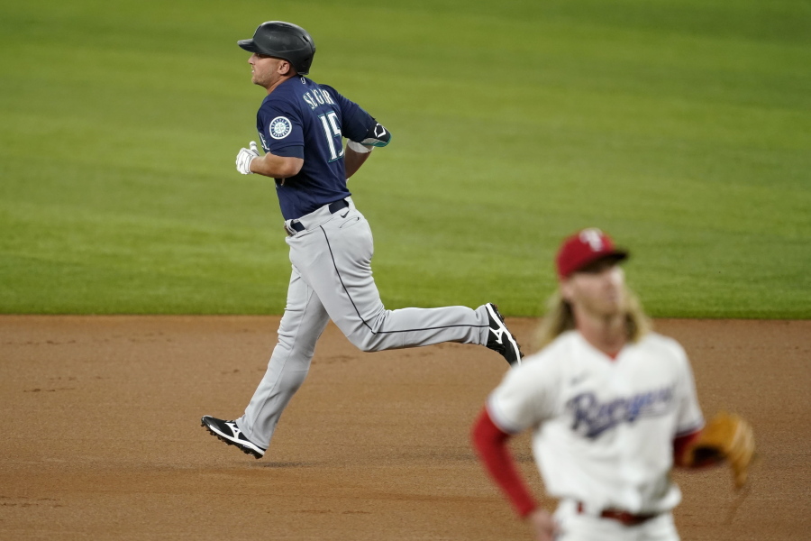 Seattle Mariners' Kyle Seager, rear, rounds the bases after hitting a two-run home run on a pitch from Texas Rangers starting pitcher Mike Foltynewicz, front, in the first inning of a baseball game in Arlington, Texas, Wednesday, Aug. 18, 2021.