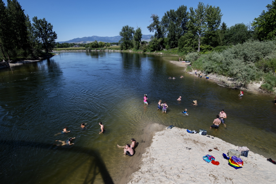 FILE - In this June 30, 2021 file photo Missoulians cool off in the Bitterroot River as temperatures crested 100 degrees Fahrenheit in Missoula, Mont. The Pacific Northwest is bracing for another major, multi-day heat wave in mid-August 2021 just a month after temperatures soared as high as 116 F in a record-shattering heat event that killed scores of the most vulnerable across the region.