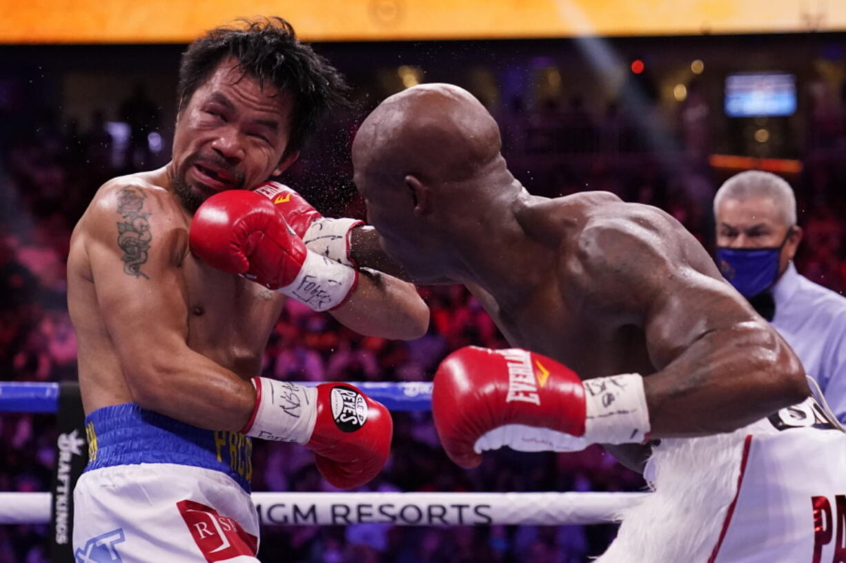 Manny Pacquiao, left, of the Philippines, is hit Yordenis Ugas, of Cuba, in a welterweight championship boxing match Saturday, Aug. 21, 2021, in Las Vegas.