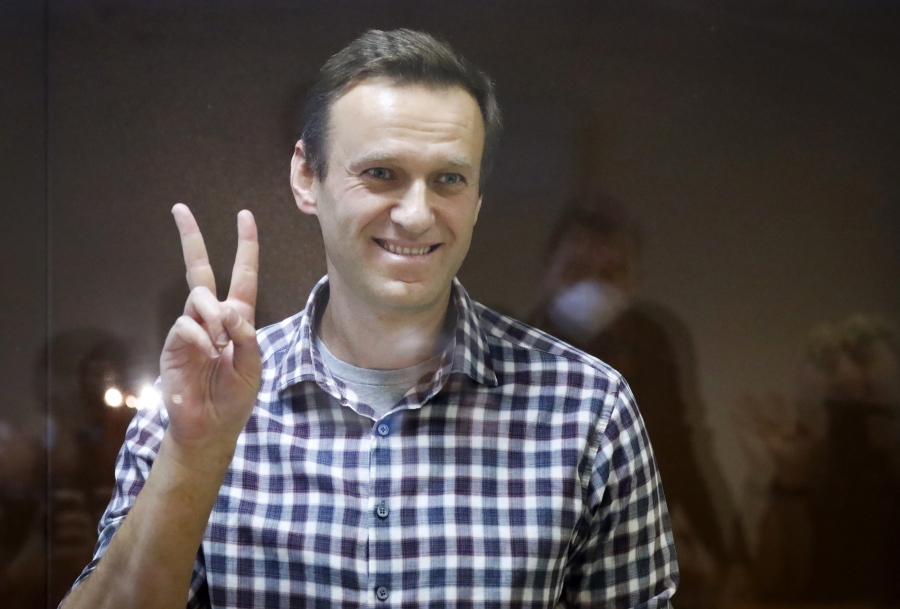 FILE - In this Saturday, Feb. 20, 2021 file photo, Russian opposition leader Alexei Navalny gestures as he stands in a cage in the Babuskinsky District Court in Moscow, Russia. Navalny marked the anniversary of a poisoning attack against him on Friday, Aug. 20 by urging global leaders to step up fight against corruption and target tycoons close to Russian President Vladimir Putin.