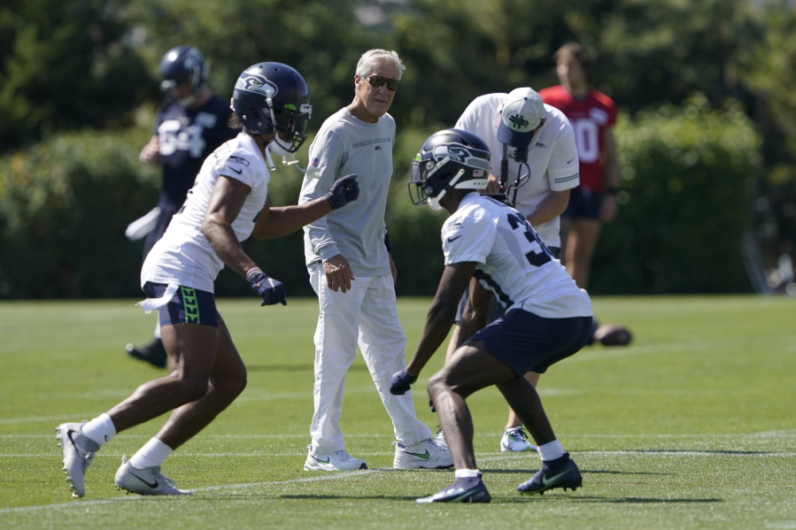 Seattle Seahawks head coach Pete Carroll, center, watches as cornerback Ahkello Witherspoon, left, runs a drill with cornerback Bryan Mills, right, during NFL football practice Thursday, July 29, 2021, in Renton, Wash. (AP Photo/Ted S.