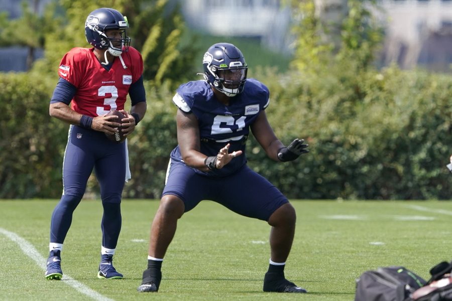 Seattle Seahawks quarterback Russell Wilson (3) takes a snap from center Kyle Fuller during NFL football practice Wednesday, Aug. 25, 2021, in Renton, Wash. (AP Photo/Ted S.
