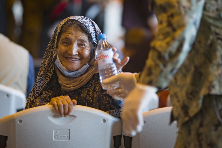 A woman from Afghanistan smiles after being given a bottle of water after disembarking from a U.S. airforce plane at the Naval Station in Rota, southern Spain, Tuesday Aug. 31, 2021. The United States completed its withdrawal from Afghanistan late Monday, ending America's longest war.